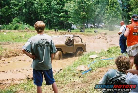 1972 Ford Bronco stuck in mud pit with people watching