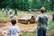 1972 Ford Bronco - A tan Ford Bronco is stuck in a mud pit while onlookers observe the scene.