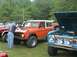 1972 Ford Bronco - A man polishes the hood of an orange Ford Bronco, with other Broncos parked nearby.