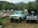 1972 Ford Bronco - Two Ford Broncos are parked at an outdoor event. The one in front has turquoise camouflage paint and a winch.
