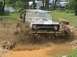 1972 Ford Bronco - A 1972 Ford Bronco navigates a muddy obstacle course, kicking up a large spray of water and dirt.