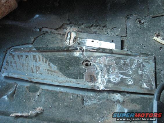 Close-up of a vehicle's floor pan with metal patches and welds, indicating repair work