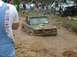 1972 Ford Bronco - A green 1972 Ford Bronco navigates a muddy off-road course, its front end submerged in the mire.