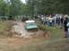 1972 Ford Bronco - A green off-road vehicle navigates a muddy track while a crowd observes the event.