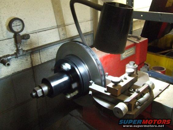 Brake rotor on lathe with gauge and black hood