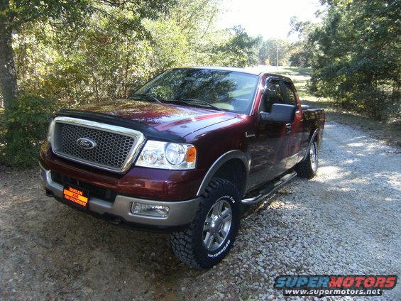 Maroon Ford F-150 pickup truck with chrome grille and BFGoodrich tires parked on a gravel road