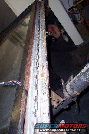 close-up of a rusted metal channel with rivets and some wires