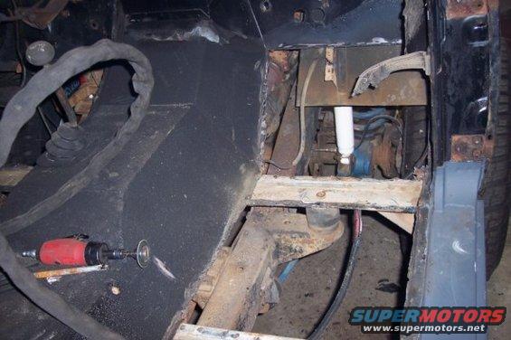 close-up of vehicle frame with suspension components and a grinder