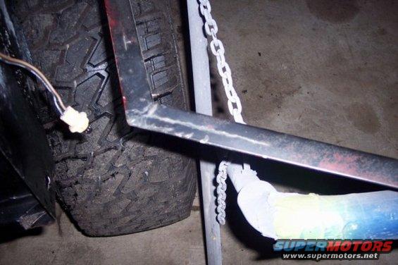 Close-up of a metal frame piece, chain, and tire tread