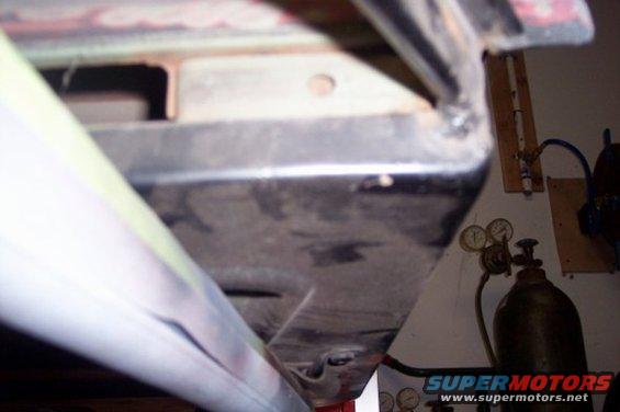 Undercarriage of a vehicle with visible welding and a gas cylinder in the background