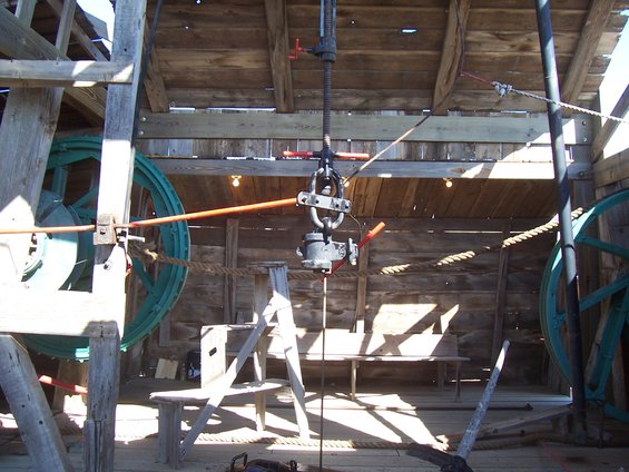 Wooden structure with large spools, ropes, and a hoist mechanism, likely for oil extraction