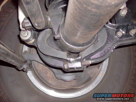 Underside view of vehicle suspension with driveshaft and tire visible
