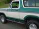 1978 Ford Bronco - This two-tone green and white Ford Bronco is shown from the front quarter angle, highlighting its side profile and off-road tires.