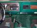 1978 Ford Bronco - Interior view of a 1978 Ford Bronco, green carpeting, woodgrain accents, and a "Bronco Graveyard" decal on the dashboard.