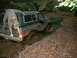 1988 Chevrolet Blazer - A person stands on the bumper of a black 1988 Chevrolet Blazer as it is stuck deep in mud.