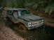 1988 Chevrolet Blazer - A 1988 Chevrolet Blazer is stuck in a muddy trail in the woods, with a person attempting to push it.
