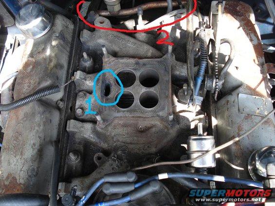 Engine intake manifold with four circular openings and various hoses and wires attached. Red and blue circles highlight specific areas