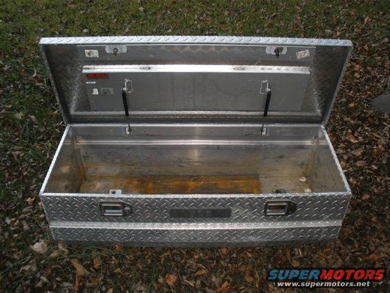 Open aluminum truck tool box with diamond plate pattern. Has two latches and gas struts on lid