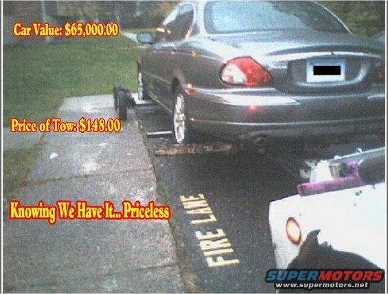 Jaguar X-Type being loaded onto a tow truck, with "FIRE LANE" painted on the asphalt