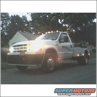 tow truck with lights on, parked on street in front of house