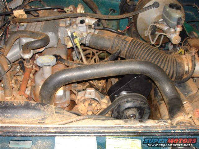 1996 Ford F-150 engine bay with dirt and grime covering components. Visible parts include hoses, belts, and the alternator