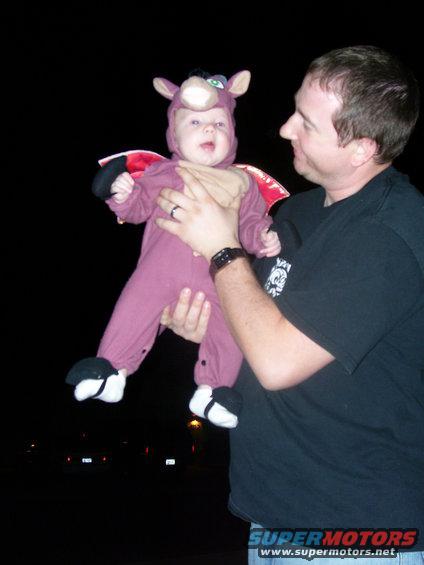 Man holds baby dressed as a purple creature with wings