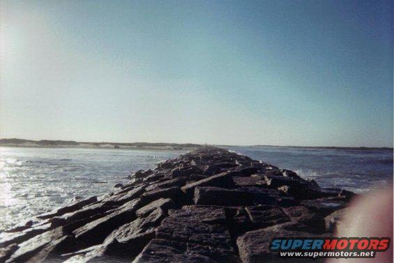 Rock jetty extends into the ocean under a clear blue sky