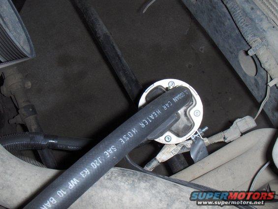 Close-up of a car heater hose with text, attached to a round component