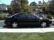 2002 Ford Taurus - A black sedan is parked on the side of the road in front of houses and trees.