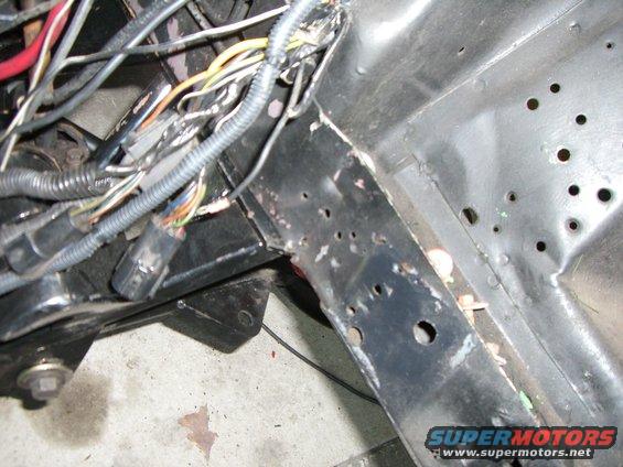 Close-up of engine bay wiring and black metal frame components