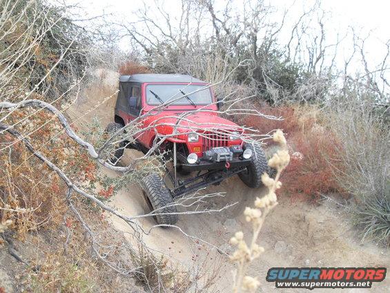 Red Jeep Wrangler on a dirt trail, front view with winch