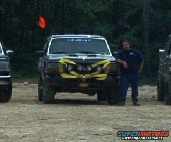 Front view of a 1993 Ford Bronco with yellow accents on the grille. Another vehicle is partially visible on the left
