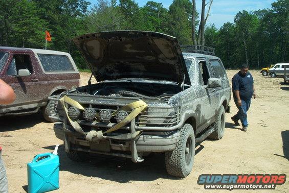Mud-covered 1993 Ford Bronco with hood open, bull bar, and auxiliary lights