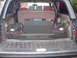1993 Ford Bronco - The cargo area of a vehicle is shown with a subwoofer, storage bags, and a cargo net.