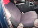 1993 Ford Bronco - The interior of a vehicle shows cloth seat covers over leather seats, a center console with cup holders, and a red bandana on the headrest.