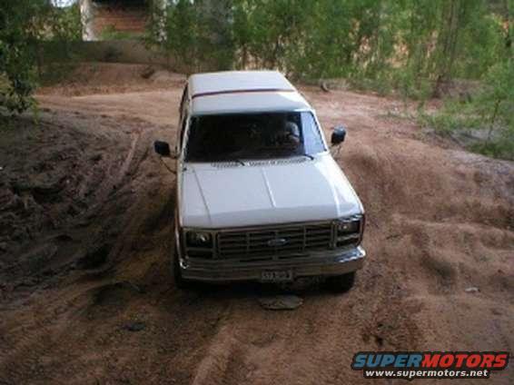 White SUV driving on a dirt path with trees in the background