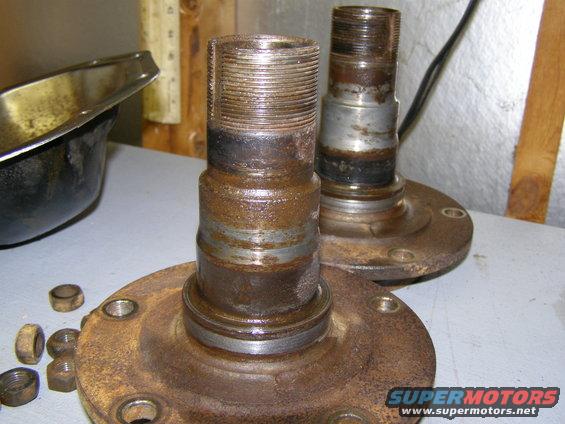 Two rusted wheel hubs with nuts on a workbench