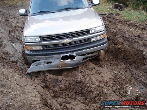 Pickup truck stuck in deep mud, front bumper hanging off