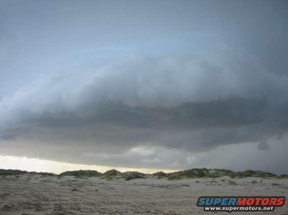Storm clouds gather over sand dunes and beach