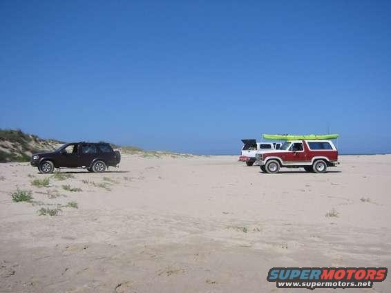 1984 Ford Bronco with kayak on roof and another SUV on beach
