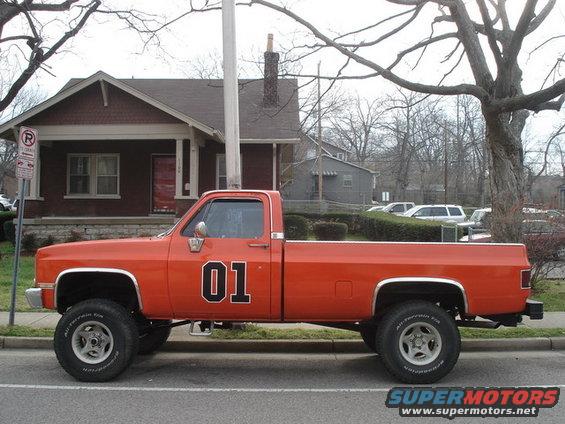 Orange pickup truck with "01" on the door, lifted suspension