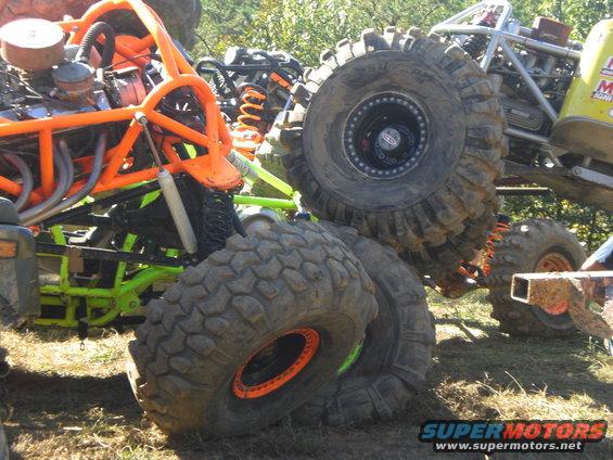 Multiple off-road vehicles with large tires and orange roll cages
