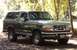 1996 Ford Bronco - A 1996 Ford Bronco is parked on a dirt road surrounded by trees.