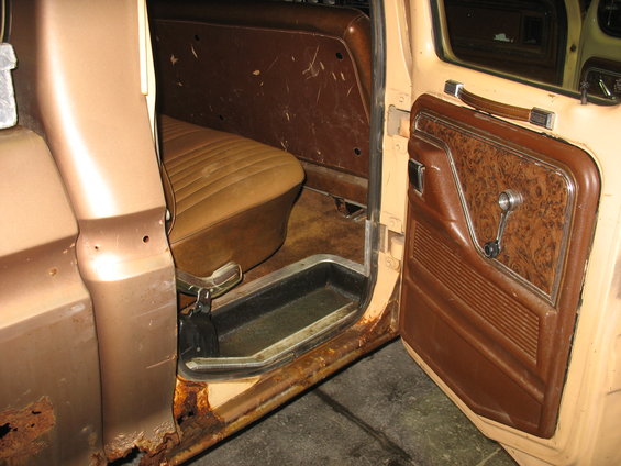 Tan interior of a 1978 Ford F-250, showing door panel, seat, and rusted rocker panel
