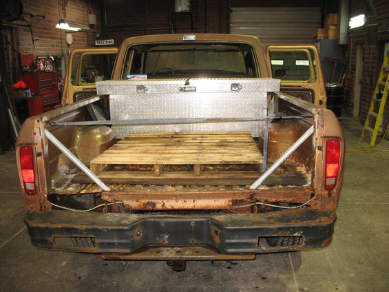 1978 Ford F-250 pickup truck rear view showing bed with toolbox and pallet, rust on bumper and bed