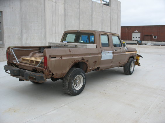 Brown pickup truck with rust and dents, toolbox in bed, snow plow attached