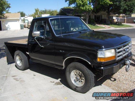 Black flatbed pickup truck, likely a 1992 Ford F-Series, parked on a driveway