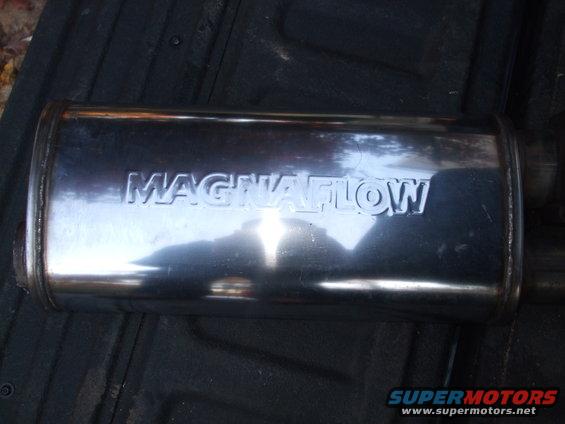 Chrome Magnaflow muffler with embossed lettering, resting on a dark surface