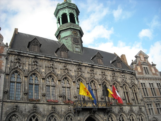 Ornate building with a green clock tower and flags flying from a balcony