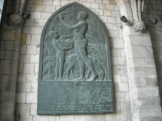 Bronze plaque on stone wall with figures and names, commemorating pioneers from 1876 to 1903